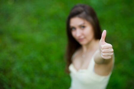 young girl shows thumb up and smiles in defocusの写真素材
