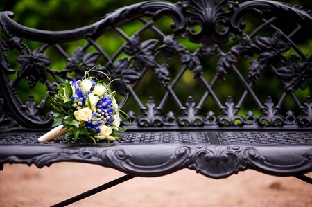 the bride s bouquet lies on the edge of an elegant cast-iron bench in the park. Close up, copy spaceの写真素材