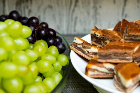 close-up of the edges of two plates standing on the distribution in the hotels dining room. Sliced pie on one plate and grapes on anotherの写真素材
