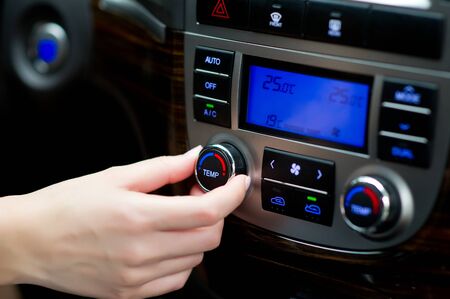 woman's hand adjusts climate control in the carの写真素材