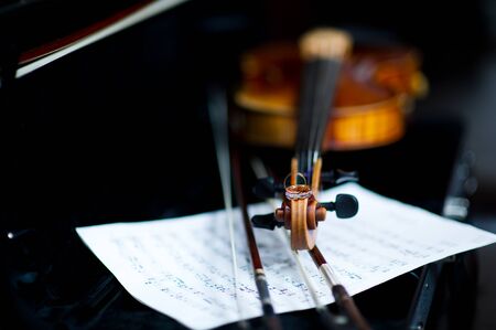 wedding rings lie on the neck of the violin against the background of musical notesの写真素材