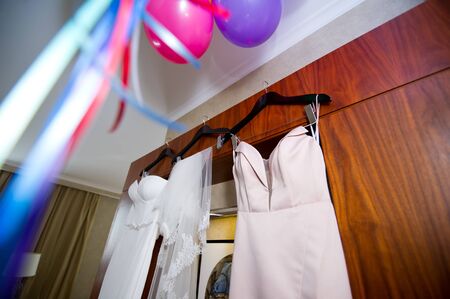 the bride s main and spare dress hangs on the front of the wardrobe, and next to the ceiling there are balls hanging and ribbons come down from themの写真素材