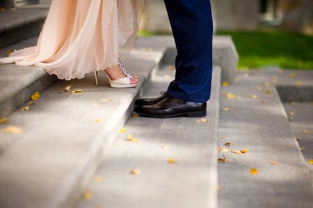 the bride and groom stand opposite each other on the steps, in the frame only legs, around are fallen autumn leaves. close upの写真素材
