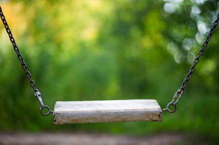 wooden swing in the village on the background of blurred greenery on a summer day. copy space