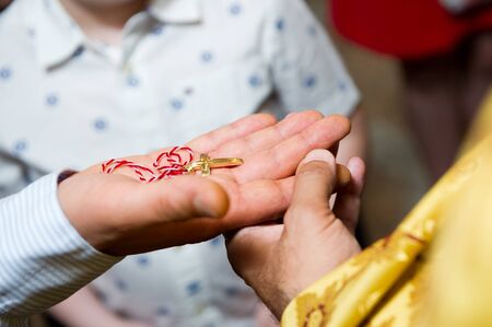 a golden cross on a red and white thread lies on the hand held by the priest. Close-upの写真素材
