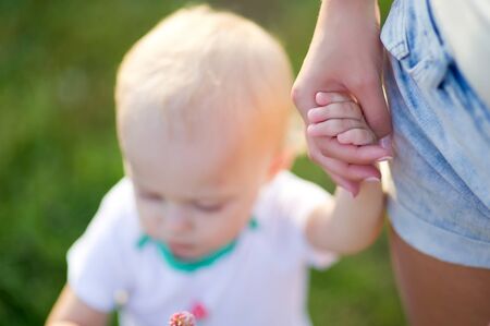 woman holds little daughter by the hand. Only hands are in focus. Close up