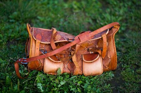 Bright orange leather bag on the grass on a summer evening.