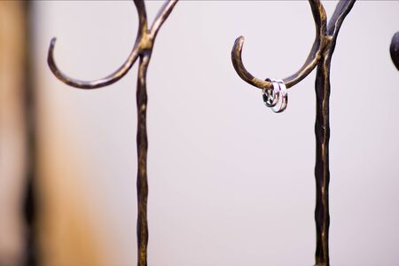 two wedding rings hanging on a decorative branch of a forged fenceの写真素材