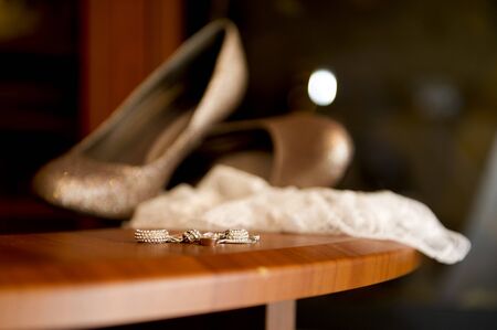 bride s earrings lie on a shelf against the background of blurry shoes and garterの写真素材