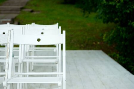 the end of a row of white seats on the pier against a green lawnの写真素材