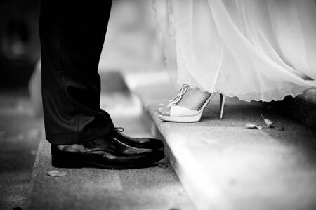 the bride and groom stand opposite each other on the steps, in the frame only legs, around are fallen autumn leaves. black and white. close upの写真素材