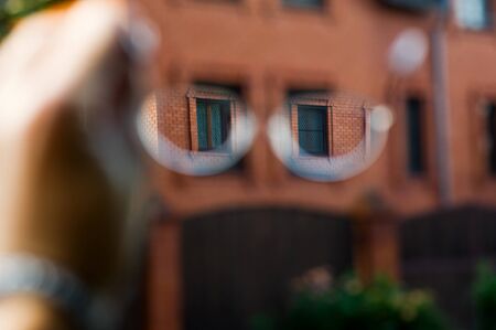look at a stone house through glasses. Selective sharpness in glasses, the rest of the space is blurry. View of the world through glassesの写真素材