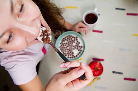 a woman is going to eat a spoonful of chocolate cereal with milk and holds a spoon in front of her....