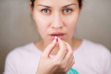 depressed young woman about to take a color pill