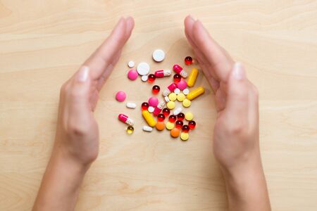 girl raked her hands in a bunch of different pills on the table. Top viewの写真素材