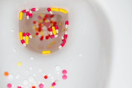 multi-colored pills float in the toilet, flush medicines into the toilet, top view