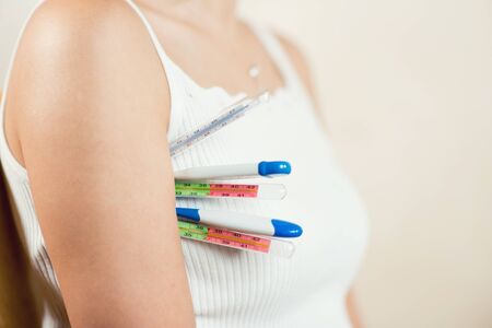 woman holds several thermometers of different types at once, copy space