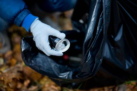 crumpled can in the hand of the employee and the trash bag, close up