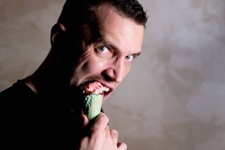 unshaven man bites an ice cream in a waffle cone. copy space