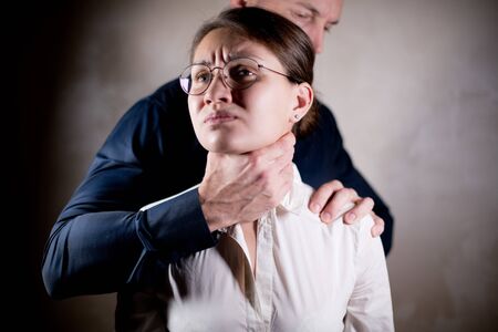 the man holds the girl by force, squeezing her throat. Domination, violenceの写真素材