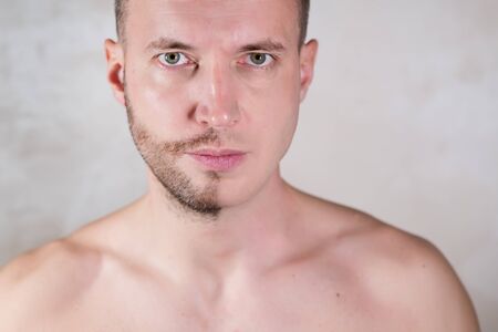 face of a young man half of which is covered with stubbleの写真素材