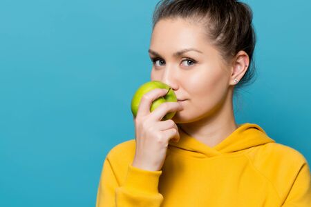 close upportrait of a girl who touches the lips of a green appleの写真素材