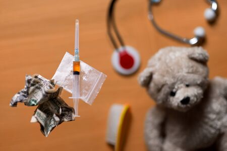 drugs are on the glass table, and on the shelf under the table are children's toys. The concept of drug problems and parenthoodの写真素材