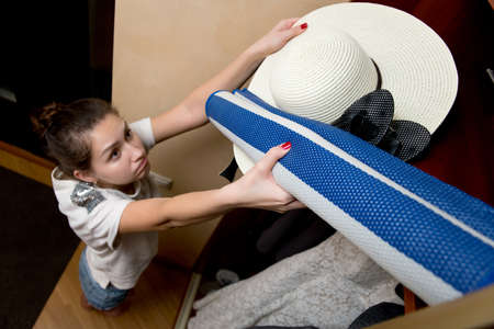 girl sadly cleans summer accessories in a closet at the end of the beach season, view from the topの写真素材