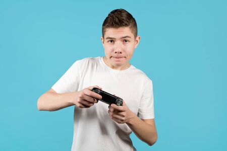 a young man with a modified without identification marks joystick is focused on the game on a blue...