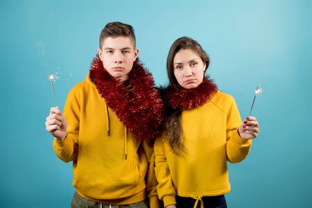 teenagers, brother and sister express apathy, but at the same time they are wearing tinsel and...