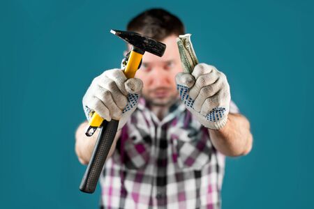 a hard worker in a crippled shirt holds out tools and crumpled dollars into the camera. Selective...