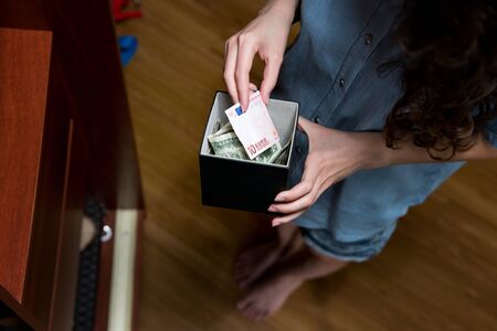 Girl recounts money in a piggy bank with dollars and euro during the crisis. Piggy bank close-up,...