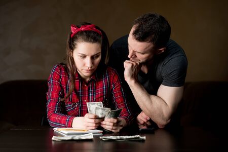 A woman counts family money, a man stands next to her and supports her