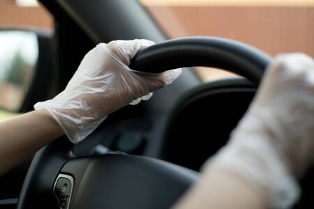 close-up of a female hand in a medical glove that holds the steering wheel in a car. Selective focus