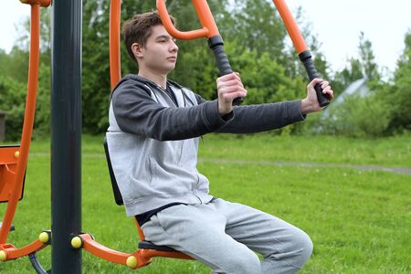A teenager is training on a machine using an athlete's own weight. Outdoor training