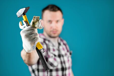 a man hands out tools and crumpled money to the camera as a symbol of hard work with low pay