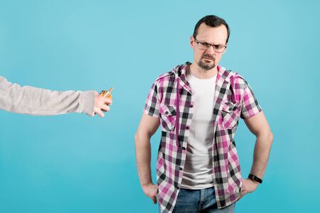 a man with condemnation and anger looks at a pack of cigarettes that another person holds out to himの写真素材