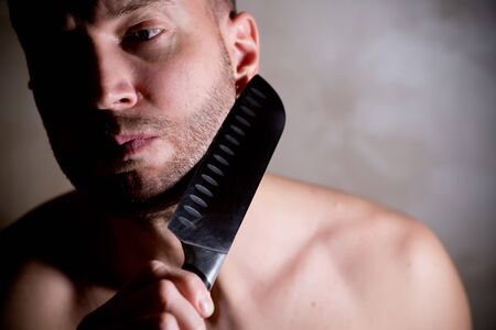 man holds a kitchen knife near his stubble on his cheek, copy spaceの写真素材