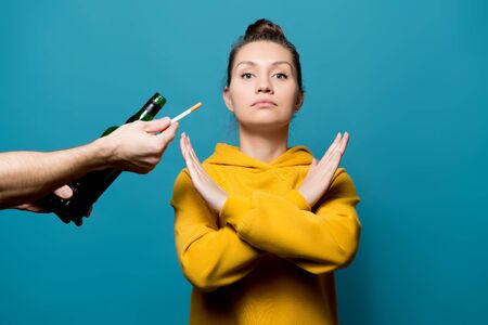 girl in a yellow sweatshirt refuses alcohol and cigarettes, preferring a healthy lifestyle