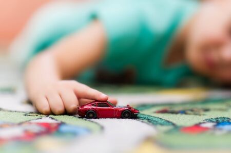 boy rolls a toy car on the floor close-up. Focus on hand and toy.の写真素材