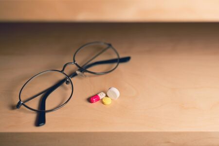 glasses for vision and tablets lies on a shelfの写真素材