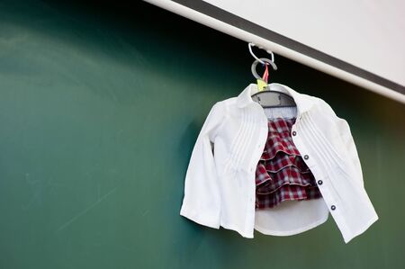 School clothes of a small child hanging on a hanger near the blackboard, bottom viewの写真素材