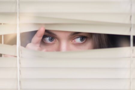 girl peeps out through the blinds, close upの写真素材