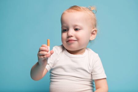 little girl in a white t-shirt examines a cigarette. Close-upの写真素材