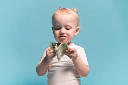little girl is looking at the dollar that she is holding in her hands. Close-upの写真素材