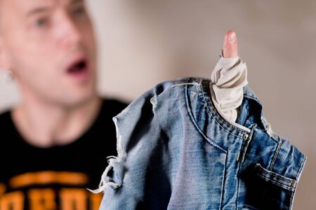 a man is surprised at the hole in his jeans pocket that he discovered, selective focusの写真素材