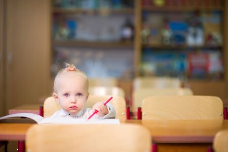 Little baby girl sitting at her desk at schoolの写真素材