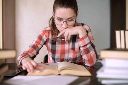 The girl is preparing for exams, looking for material in a book, leafing through it. Does not find...