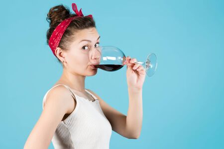 Close-up of a girl with a glass of wine on a blue backgroundの写真素材
