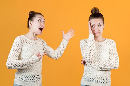 Split personality. The girl chastises herself and resists this herself. Both women - one and the same face, montage on an orange backgroundの写真素材